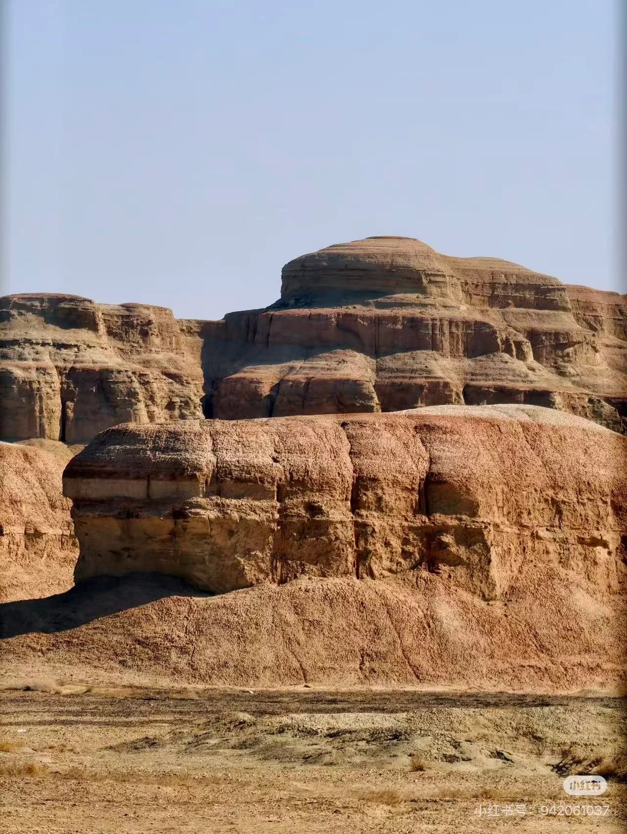 Morning light on the yardang formation at Dunhuang, with flat-topped earthen towers rising from the desert floor and casting long shadows across the gravel plain