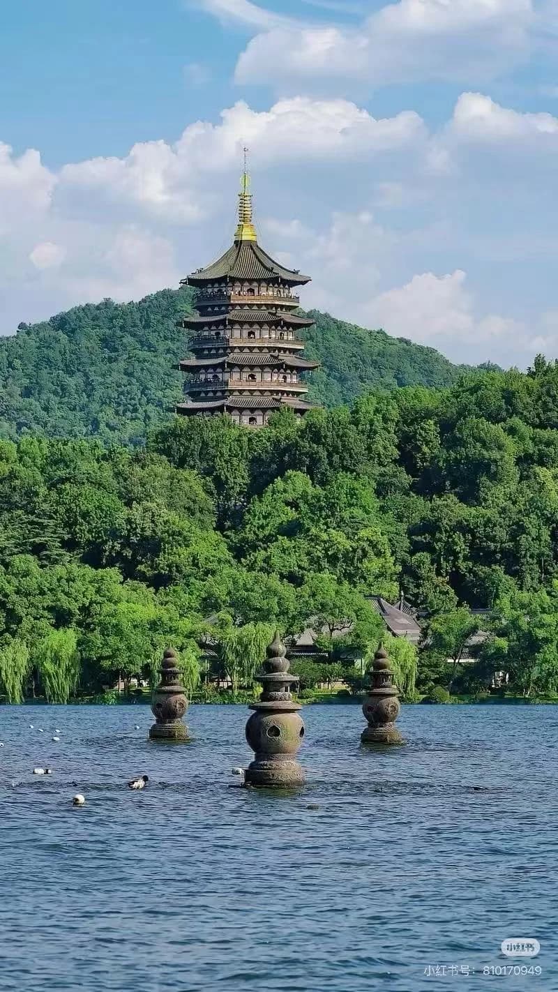 The Leifeng Pagoda standing atop a lush green hill overlooking the Three Pools Mirroring the Moon at West Lake.