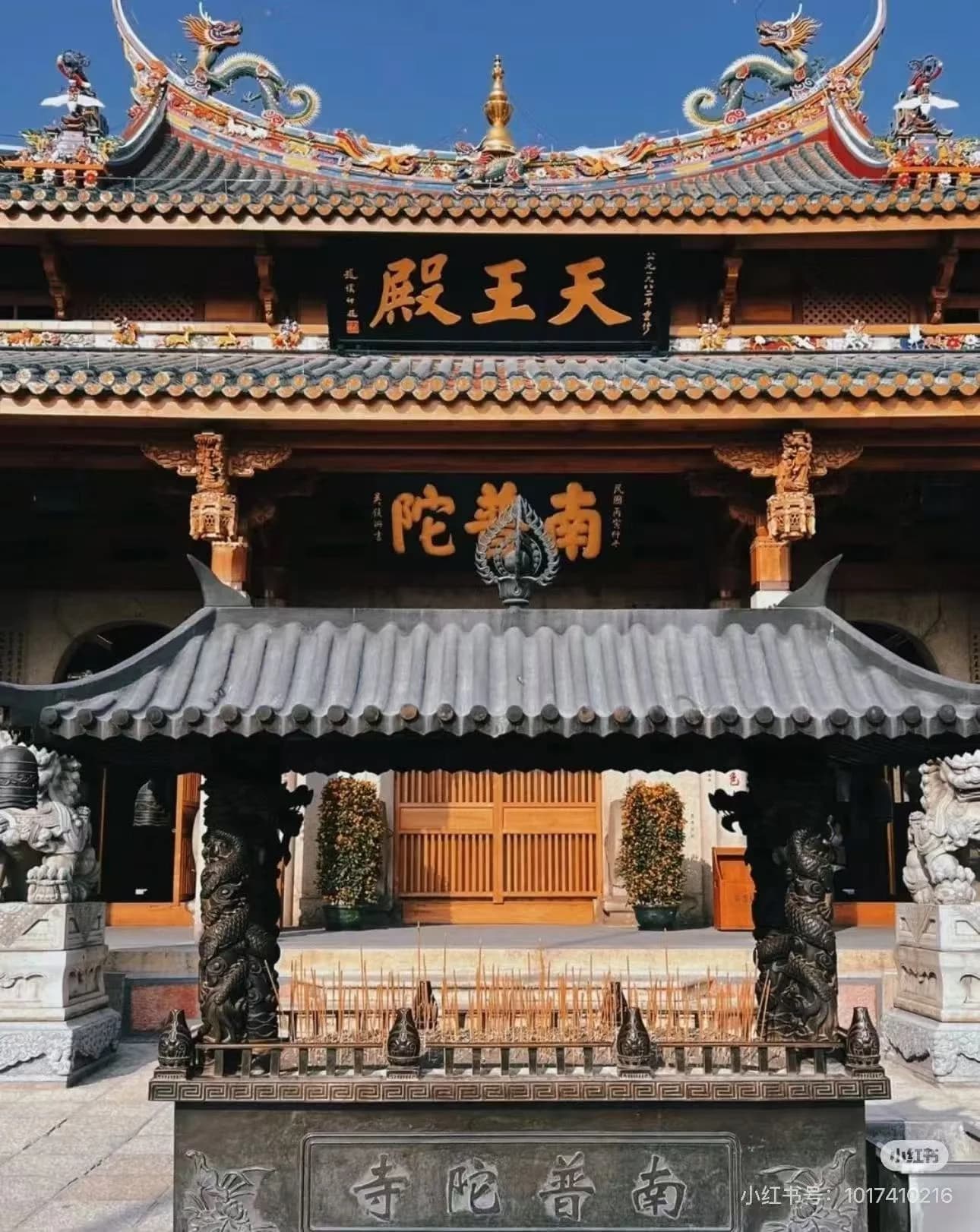 Red-walled Buddhist temple with octagonal tower nestled between mountains and sea in Xiamen