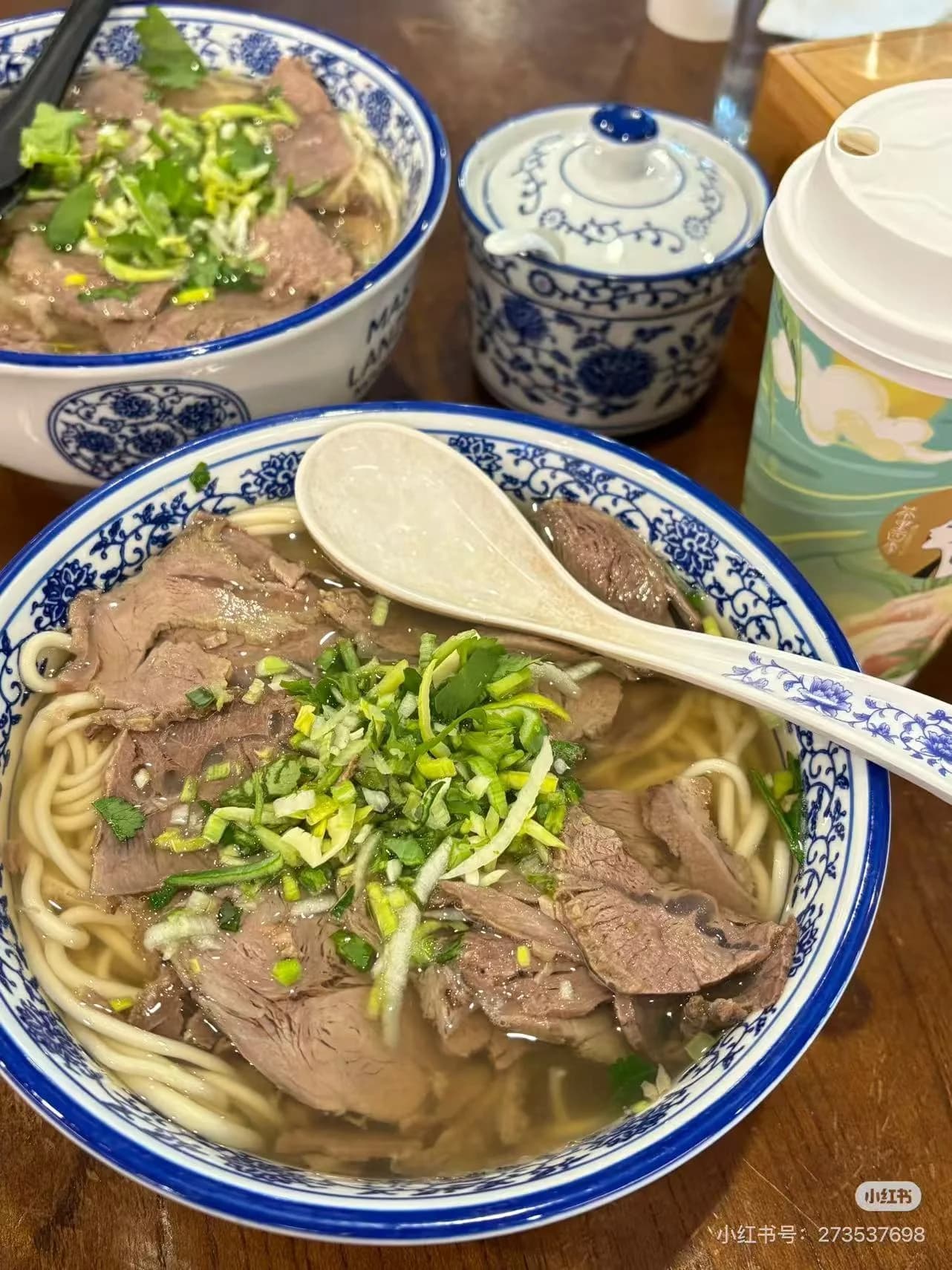Bowl of Lanzhou beef noodles with clear broth, sliced beef, and chili oil