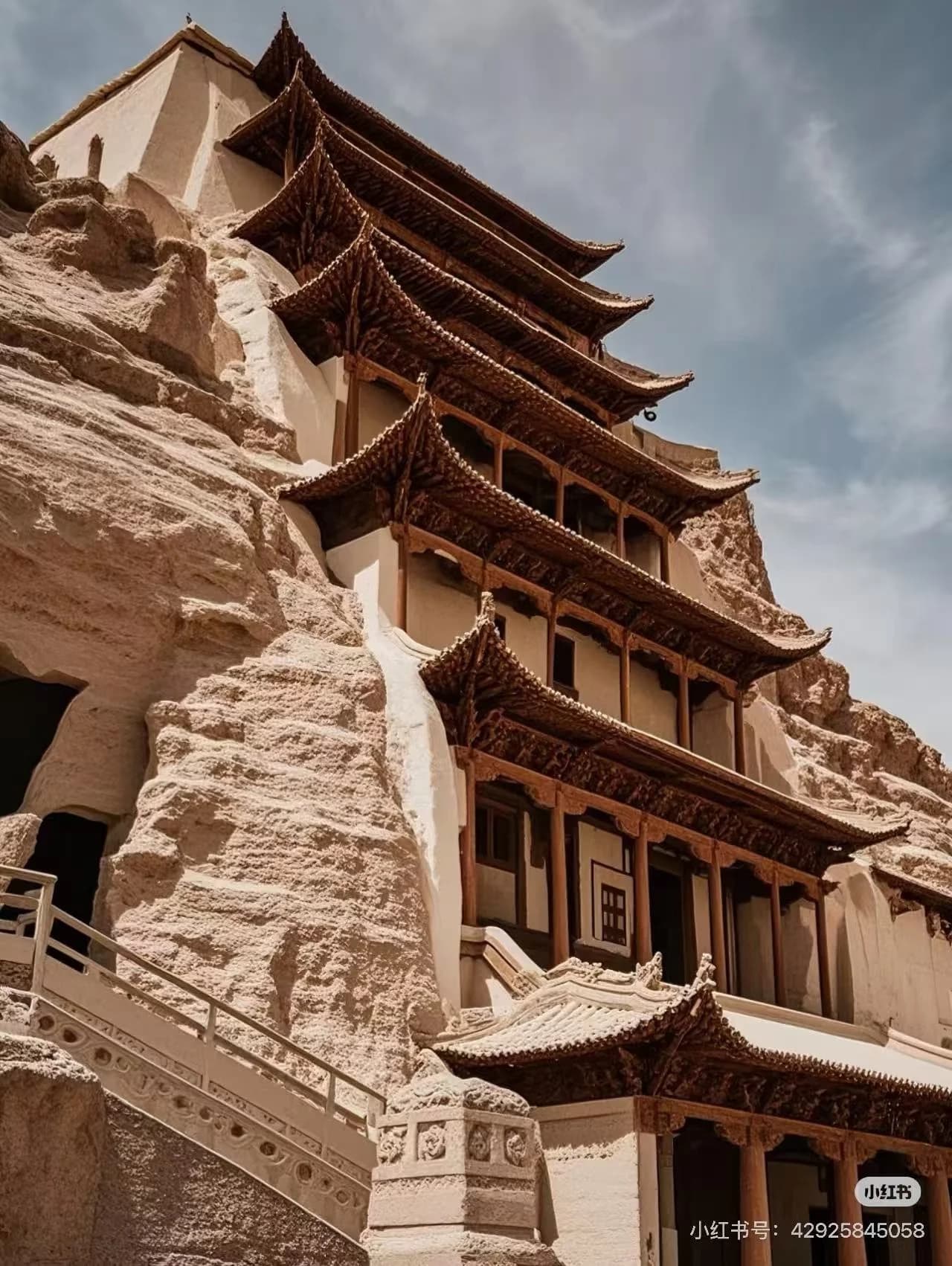 The Mogao cliff face with its honeycomb of cave entrances cut into pale brown rock against a clear desert sky
